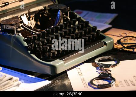 Macchina da scrivere retrò, manette e fascicoli criminali sul tavolo scuro, primo piano Foto Stock