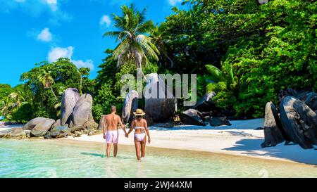 Un paio di uomini e donne sulla spiaggia dell'isola tropicale di Praslin Seychelles Foto Stock