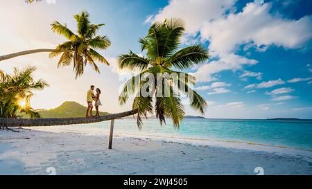 Isola tropicale di Praslin Seychelles con spiagge e palme, coppia di uomini e donne con palme che guardano il tramonto Foto Stock