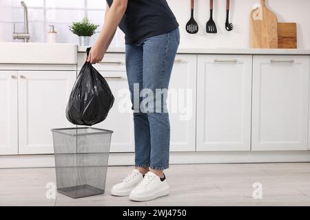 Donna che prende la spazzatura dal cestino della spazzatura in cucina, primo piano Foto Stock