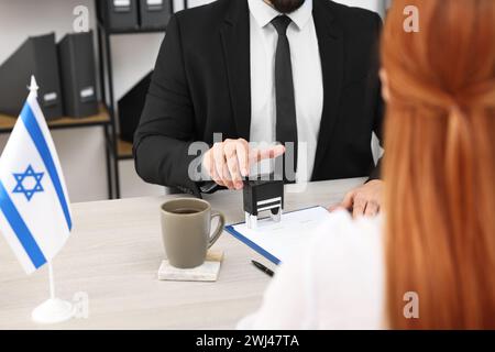 Immigrazione in Israele. Lavoratrice dell'ambasciata che approva il modulo di domanda di visto per una donna in carica, primo piano Foto Stock