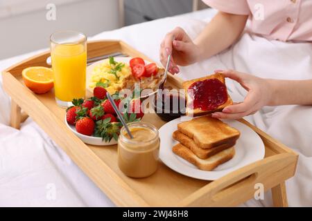 Donna che fa una gustosa colazione a letto, primo piano Foto Stock