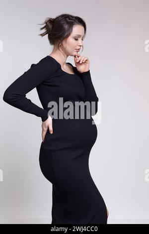 Ritratto di una giovane donna incinta in abito nero. Foto Stock