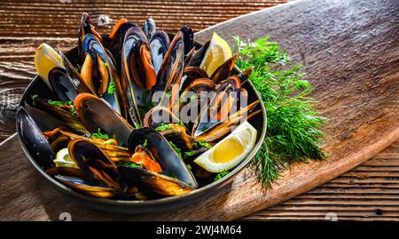 Composizione con un piatto di cozze al vapore servito con prezzemolo e limone Foto Stock