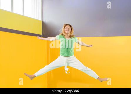 Giovane ragazza che salta su un trampolino nel centro sportivo Foto Stock