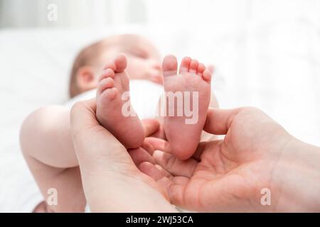 I piccoli piedi del neonato mantenuti con cura, concetto di abbraccio protettivo di una madre Foto Stock