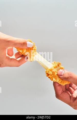 I bastoncini di mozzarella impanata e croccanti di formaggio si allungano a due mani Foto Stock