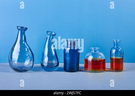 Set di vari flaconi e vasi in vetro e metallo colorati e silenziosi su sfondo blu. Foto Stock