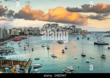 Tramonto sulla baia di Sliema a Malta. Nuvole e barche Foto Stock