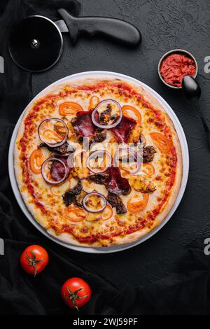 Pizza sul tagliere con taglierina nelle vicinanze, vista dall'alto Foto Stock