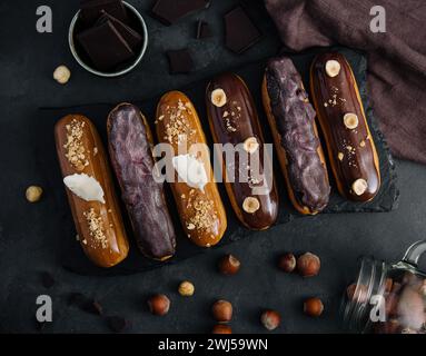 Dolci eclari di cioccolato su tavola di legno nera Foto Stock