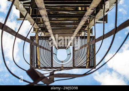 Vecchia scala arrugginita con danni contro il cielo blu e le nuvole Foto Stock