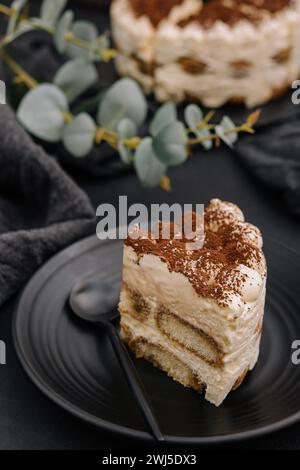 Tradizionale tiramisù italiano su piatto nero Foto Stock