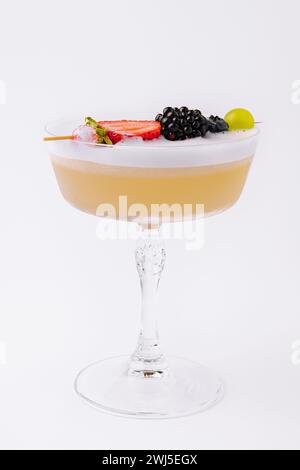 Primo piano cocktail giallo con schiuma bianca e frutti di bosco Foto Stock