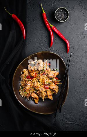 Mescolare gli spaghetti con verdure e pollo in un recipiente nero Foto Stock