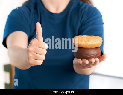 Vista frontale ravvicinata di una donna che tiene le ciambelle a casa Foto Stock