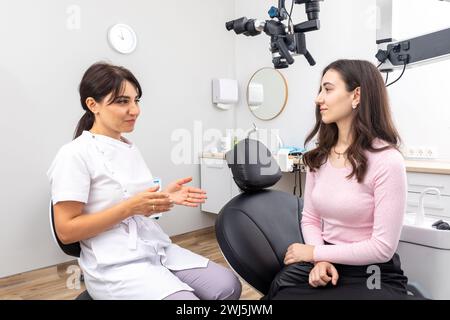 Dentista femminile che spiega il trattamento del paziente durante un appuntamento in clinica odontoiatrica Foto Stock