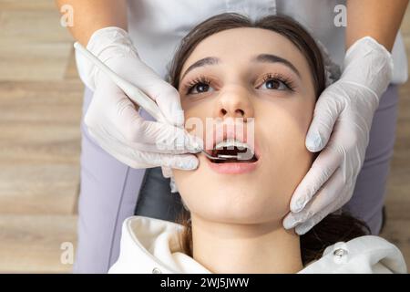 Dentista che esamina i denti del paziente con specchio dentale Foto Stock