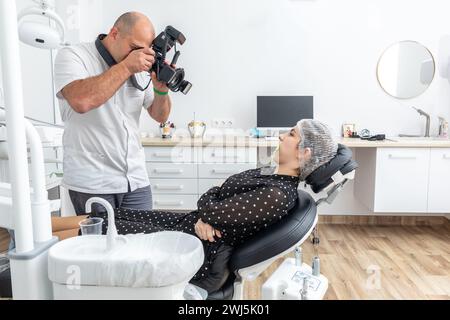 Dentista fotografando i denti del paziente per cartella medica prima e dopo l'intervento chirurgico in studio dentista Foto Stock