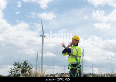 Gli ingegneri utilizzano uno smartphone per controllare la turbina eolica sul campo, il concetto di energia naturale dal vento. Foto Stock