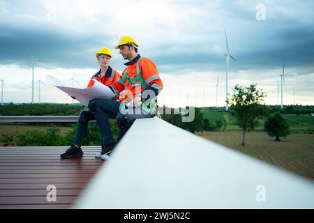 Ingegnere e tecnico che discutono del progetto sul cantiere con background sulle turbine eoliche Foto Stock