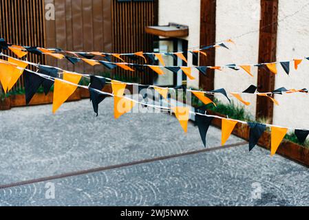 Bandiere arancioni e nere di Halloween appese su una strada all'aperto, per celebrare le festività autunnali. Foto Stock