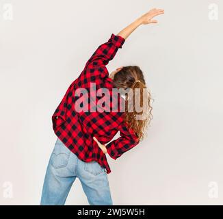 Vista posteriore casual che indossa una giovane donna che fa esercizi di stretching del corpo. Foto Stock