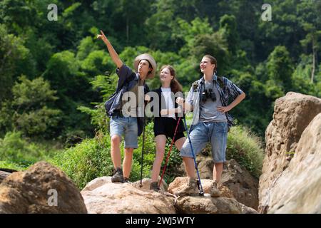 Gruppo di turisti con zaini che camminano lungo il sentiero del fiume e delle montagne Foto Stock