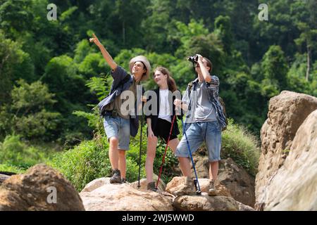 Gruppo di turisti con zaini che camminano lungo il sentiero del fiume e delle montagne Foto Stock