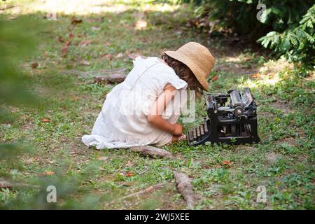 Little Girl in Hat Typewriter su Antique Typewriter Foto Stock