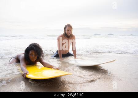 Giovane uomo e donna che si divertono con la tavola da surf nell'oceano in una giornata di sole Foto Stock