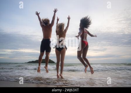 Gruppo di amici che si divertono sulla spiaggia al tramonto. Foto Stock