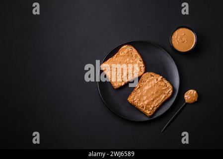 Sandwich nutriente composto da pane e burro di arachidi su un piatto di ceramica nera Foto Stock