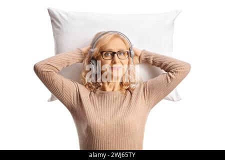 Donna di mezza età con cuffie appoggiate su un cuscino isolato su sfondo bianco Foto Stock