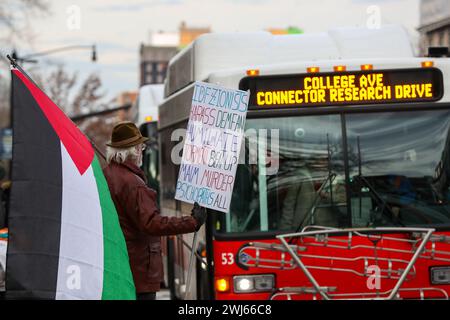 State College, Stati Uniti. 12 febbraio 2024. Greg Connolly, membro della comunità dello State College, detiene una bandiera palestinese e un cartello fatto a mano presso Allen Street e College Avenue vicino ai cancelli di Allen Street della Penn State. Credito: SOPA Images Limited/Alamy Live News Foto Stock