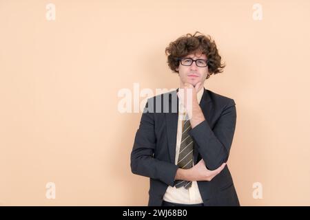 Ritratto di un bel giovane con capelli ricci su sfondo beige Foto Stock