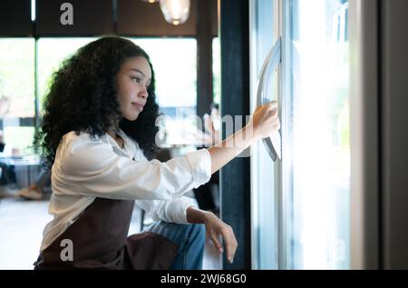 Il proprietario di un bar guarda all'interno del frigorifero per recuperare cibo fresco e servire un cliente. Foto Stock