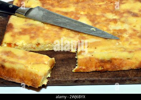 Una torta cotta con formaggio fresco e zucca giace su un tagliere. Foto Stock