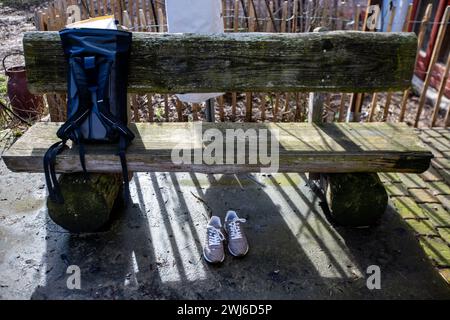 Ruhner Berge, Germania. 13 febbraio 2024. Le scarpe da ginnastica di Steffi Lemke (Alleanza 90/Verdi), ministro federale dell'ambiente, della conservazione della natura, della sicurezza nucleare e della tutela dei consumatori, si trovano di fronte a una panchina di legno nell'azienda casearia gestita con metodo biologico sulle colline Ruhn al confine tra Brandeburgo e Meclemburgo-Pomerania occidentale. Il ministro indossa stivali di gomma durante un tour delle scuderie. Siebengiebelhof è una piccola azienda agricola con 25 mucche da latte al pascolo, caseificio proprio, commercializzazione diretta e metodi di agricoltura biologica. Crediti: Jens Büttner/dpa/Alamy Live News Foto Stock