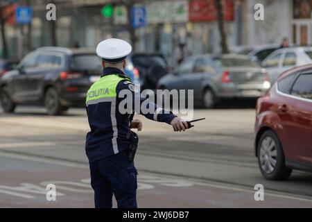 Bucarest, Romania - 13 febbraio 2024: L'agente rumeno della polizia stradale gestisce il traffico su una strada trafficata. Foto Stock