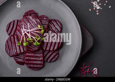 Deliziose barbabietole bollite color rubino tagliate a fette su un piatto nero Foto Stock