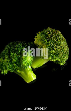 Broccoli verdi con sfondo nero scuro in verticale Brassica oleracea var italica Foto Stock