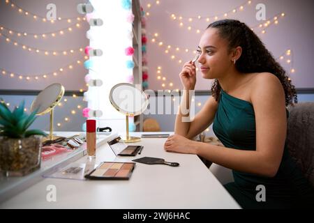 Adolescente a casa in camera da letto prepararsi per il ballo o la notte fuori mettendo su trucco Foto Stock