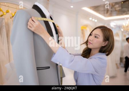 Gli stilisti asiatici si assicurano che l'outfit dello sposo sia assolutamente accurato e pronto per la sposa e lo sposo da provare. Foto Stock