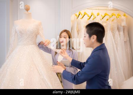 Entrambi gli stilisti asiatici che lavorano con abiti da sposa nel negozio di abiti da sposa Foto Stock