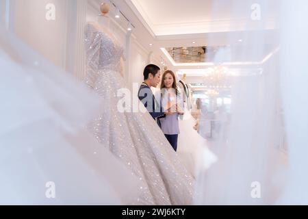 Entrambi gli stilisti asiatici che lavorano con abiti da sposa nel negozio di abiti da sposa Foto Stock