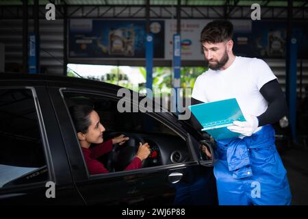 Una giovane donna porta la sua auto dal meccanico per portarla a ispezionare e manutenere in base al periodo di ispezione della vettura Foto Stock