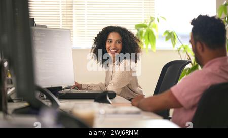 Colleghi di lavoro maschili e femminili che lavorano insieme al computer in ufficio Foto Stock