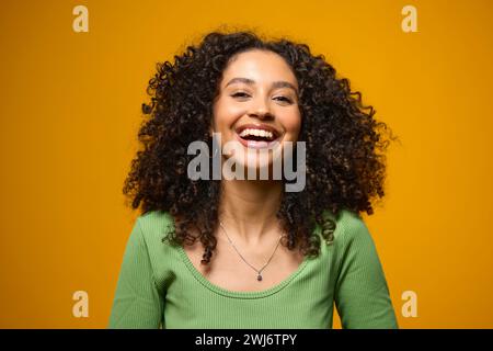 Studio Ritratto di donna sorridente in piedi su sfondo giallo Foto Stock
