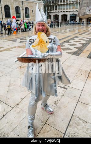 Londra, Regno Unito. 13 febbraio 2024. L'annuale Inter-Livery Pancake Races normalmente a Guildhall Yard il martedì grasso, ma quest'anno a causa delle piogge è stato spostato nella cripta. Le squadre che indossano abiti eleganti o abiti completi, corrono intorno al Guildhall Yard lanciando le loro frittelle. La competizione è in corso ogni anno da oltre 15 anni e i proventi vanno a cause di beneficenza. Crediti: Guy Bell/Alamy Live News Foto Stock